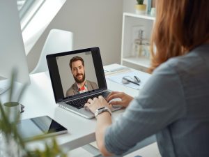 A realistic home office setup with a person attending a video call on a laptop,