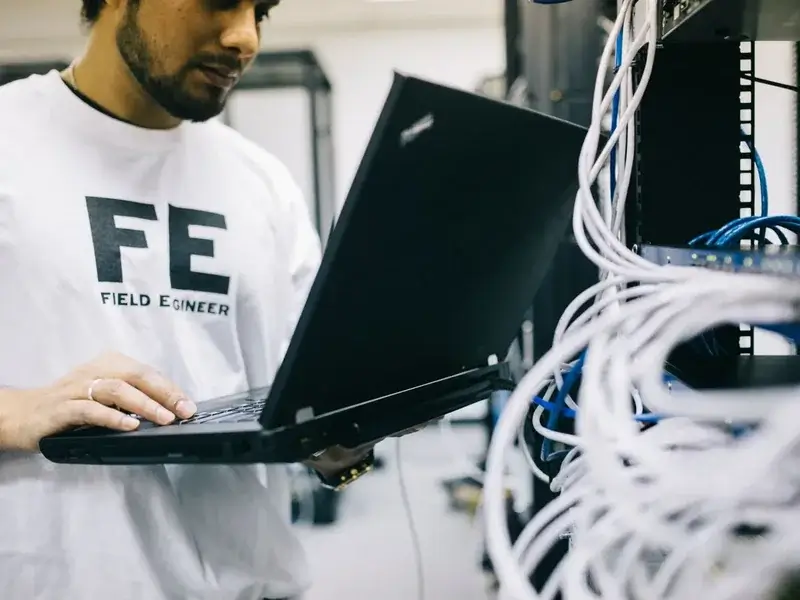 Field engineer using a laptop beside a network rack while configuring gateway and SBC settings