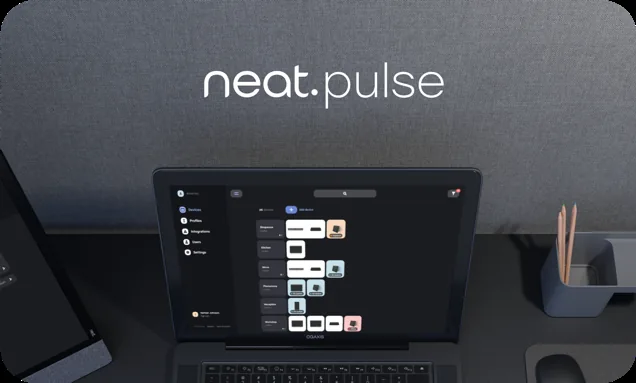 Neat Pulse cloud management dashboard showing device status across meeting rooms, viewed on a laptop